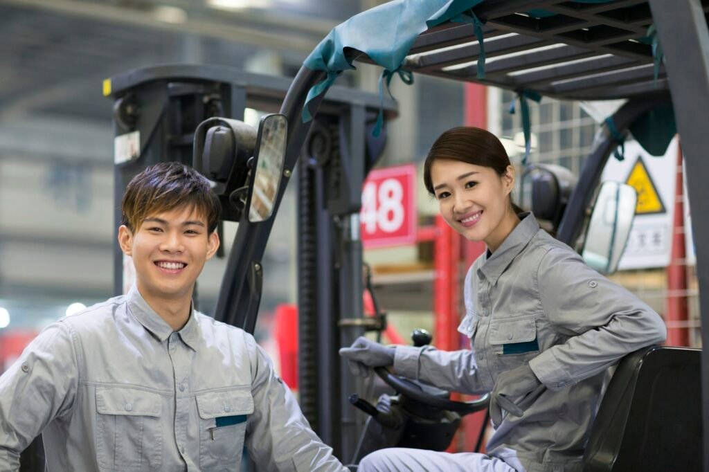 Confident workers driving forklift in the factory